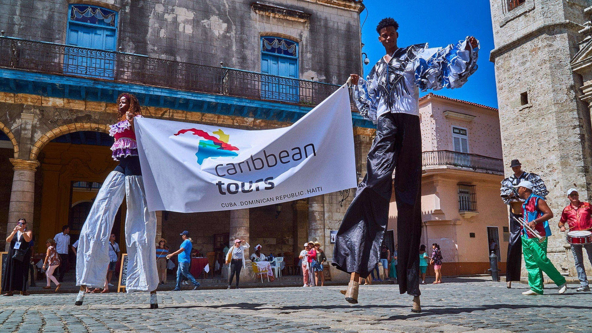 Stilt walkers with flag of Caribbean Tours